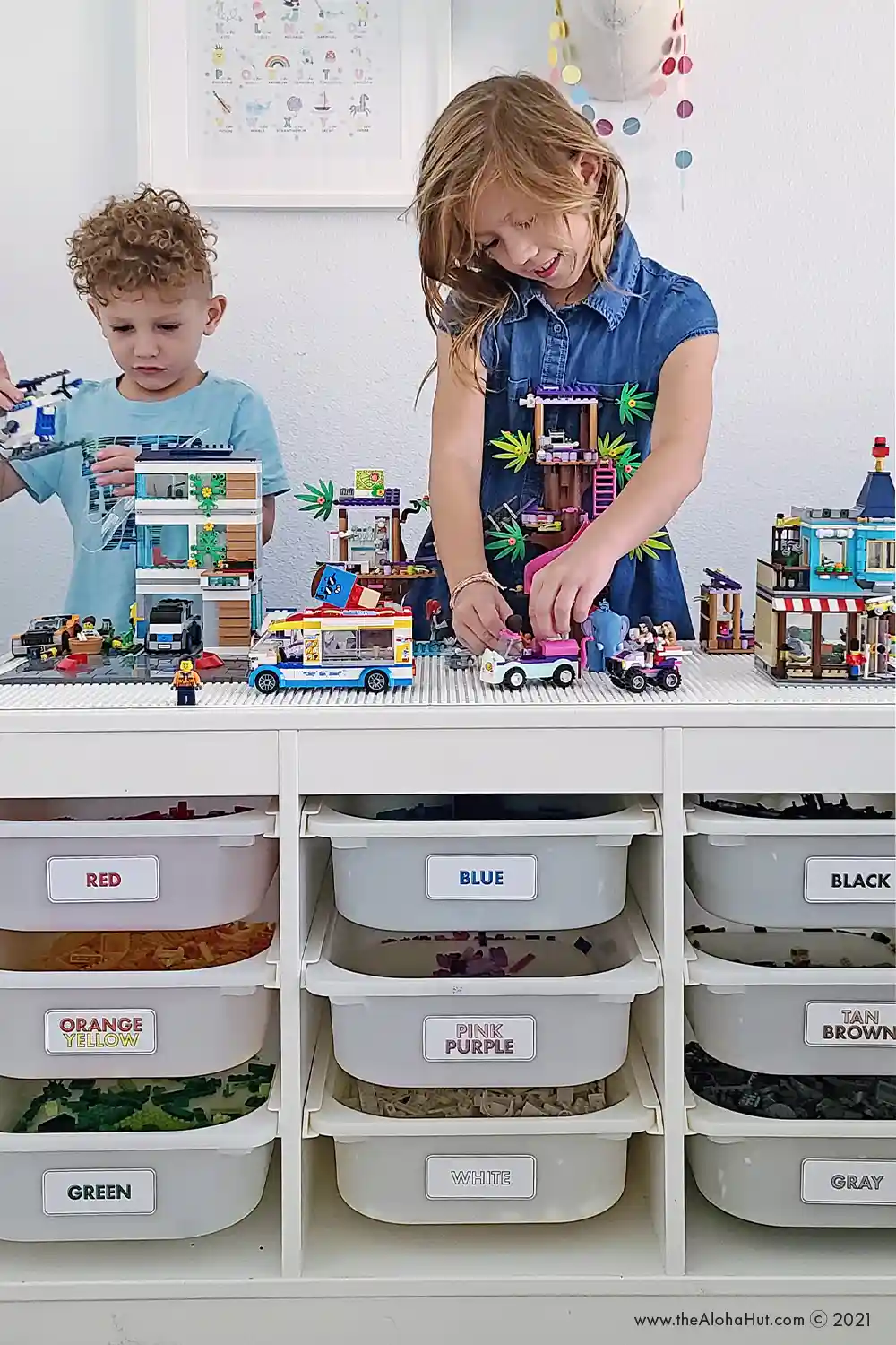 Kids playing with LEGO on LEGO baseplates that are attached to the top surface of an Ikea Trofast unit,